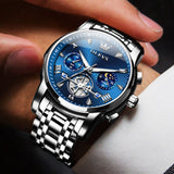 Luxury watch with blue face and silver strap worn on a wrist