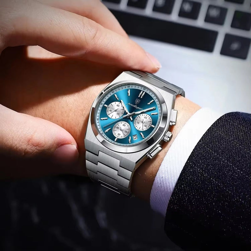 Hand wearing a silver watch with a blue face on a blurred keyboard background